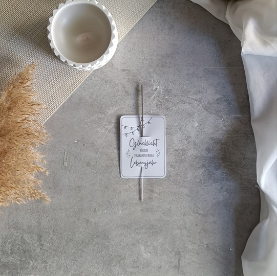 DIY-Geburtstagskarte mit Wunderkerze und der Aufschrift „Glückslicht für ein strahlendes neues Lebensjahr“, dekoriert mit Kerze, Pampasgras und Leinenstoff auf hellem Untergrund.